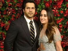 a man and woman standing next to each other in front of a flowery wall