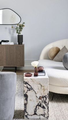 a living room filled with furniture and a marble table in front of a mirror on the wall