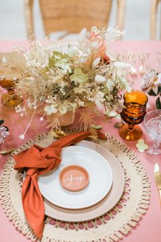 a table set with plates, napkins and flowers