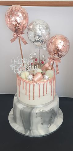 a white cake with pink icing and balloons on top