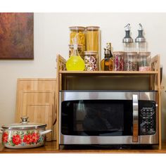 a microwave oven sitting on top of a wooden shelf next to a pot and pan