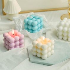 three candles are sitting on a table with white and blue balls in the middle of them