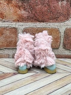 a pair of pink slippers sitting on top of a wooden floor next to a brick wall