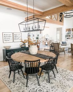 the dining room table is surrounded by black chairs and an area rug that matches the hardwood flooring