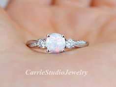 a white opal and diamond ring on someone's hand