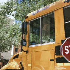 a yellow school bus parked in front of a building with a stop sign on it