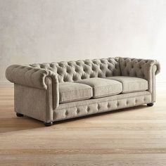 a beige couch sitting on top of a hard wood floor next to a white wall