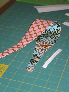 a pair of scissors sitting on top of a cutting board next to some tape and paper