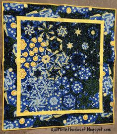 a blue and yellow square quilt with stars on the center, surrounded by small white flowers