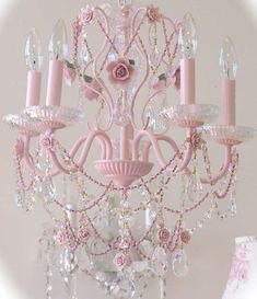 a pink chandelier hanging from the ceiling with crystal beads and roses on it