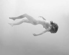 a naked woman floating in the air with her legs spread out and head above water