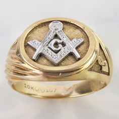 A large white gold square and compass symbol tops this vintage 10k yellow gold Masonic ring. The 3/8 inch symbol is recessed in a matte golden oval. A shiny yellow gold trim frames it. The shoulders are adorned with the plumb and trowel symbols with asymmetrical placement. The shoulders have a carved ribbed design. The ring was finished with a thick sturdy 3.3mm wide shank band. The inside is hallmarked, "10k" (gold) and signed "JTC" with number "107". It currentyly measures an approx. size 7.75 and could be re-sized to an extent. It is in very good vintage condition with general surface wear to the gold. Please see photos for condition and detailed measurements below. This piece is a very fine example of a classic Masonic ring with a somewhat unique styling. Wt: 6.5 grams US Ring size : 7 Classic Compass Design Jewelry For Anniversary, Classic Jewelry With Compass Design For Anniversary, Classic Formal Jewelry With Compass Design, Compass Symbol, Masonic Ring, Large White, 10k Gold, Compass, Gold Trim