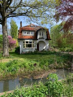 a white house sitting on top of a lush green field next to a forest filled with trees