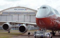 an airplane is parked in front of the air france hangar with its door open and people walking around it