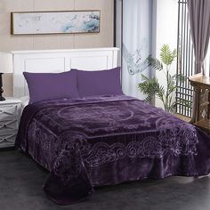 a bed with purple sheets and pillows in a room