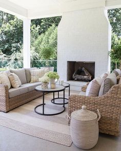 a living room with wicker furniture and a fire place in the middle of it