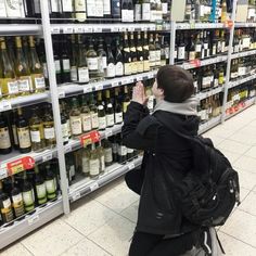 a woman sitting on a chair in front of shelves filled with wine and liquor bottles