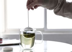 a person is holding a tea in a glass cup