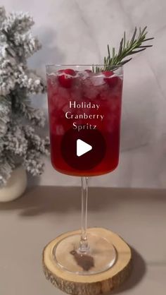 a holiday cranberry spritz cocktail in a wine glass on a wooden coaster