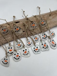 six snowmen with orange noses and black dots on them are hanging from a piece of driftwood