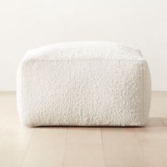 a large white ottoman sitting on top of a hard wood floor next to a wall