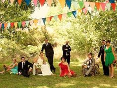 a group of people standing and sitting in the grass with flags behind them on a sunny day