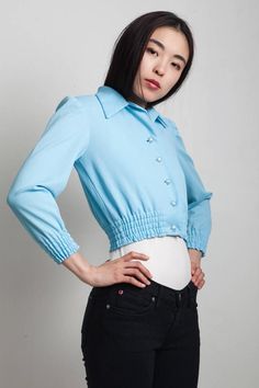 vintage 60s blue jacket top EXTRA SMALL / SMALL XS S cropped, long sleeves 5 square buttons, center front closure elastic hemline and wrists ----- Measurements (taken flat) Shoulders : 14.5 Bust (flat x 2) : 34 Waist (flat x 2) : 22-28 (elastic) Hips (flat x 2) : - Length : 16.5 Sleeve Length : 20 Fitted Light Blue Outerwear With Buttons, Blue Cropped Jacket With Button Closure, Fitted Blue Cropped Jacket, Fitted Cropped Blouse With Button Cuffs, Fitted Blue Top With Button Cuffs, Fitted Blue Tops With Button Cuffs, Blue Button-up Cropped Jacket For Spring, Blue Buttoned Cropped Jacket For Fall, Blue Cropped Jacket With Buttons For Fall