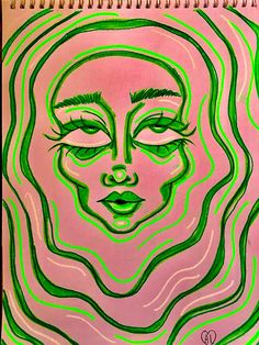 a drawing of a woman's face is shown in green and pink colors on a spiral notebook