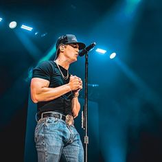 a man standing in front of a microphone on top of a stage with lights behind him