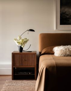 a bedroom with a bed, nightstand and plant on it's side table in the corner