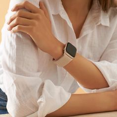 a woman is sitting down with her arm on the table and wearing a white shirt