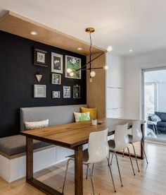 a dining room table with white chairs next to a bench and pictures on the wall