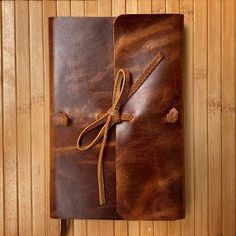 a brown leather journal on top of a wooden table