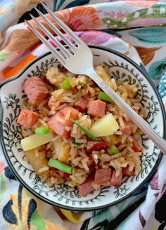 a bowl filled with rice, ham and pineapples on top of a colorful table cloth