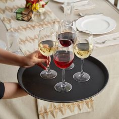 three glasses of wine are being served on a black tray with white and red wine