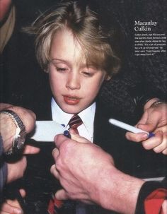 a young boy in a suit and tie getting his tie put on by an older man