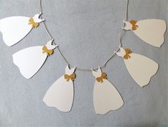 a white necklace with five brides cut out of paper hanging from it's sides