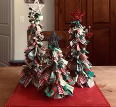 two christmas trees made out of paper on top of a red box with white and green bows