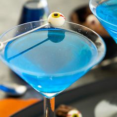 two martini glasses with blue liquid and an eyeball on the rim