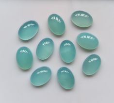 seven blue glass eggs sitting on top of a white table