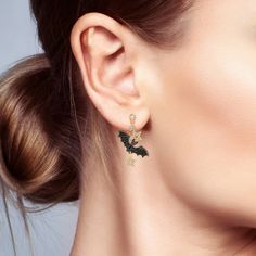 a close up of a woman's ear wearing gold earrings with green and white crystals