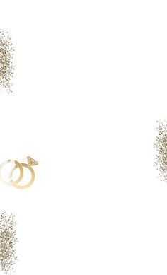 two wedding rings surrounded by glitter on a white background