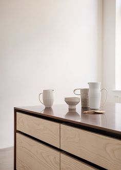 two cups are sitting on top of a dresser