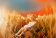 a woman sitting in the middle of a field with her legs crossed and eyes closed