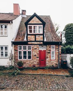 a brick house with a red door and windows on the side of it's building