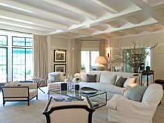 a living room filled with white furniture and lots of windows