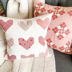 two pillows with hearts on them sitting on a couch