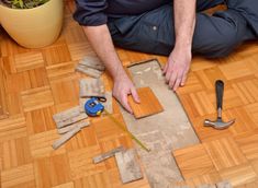 a man sitting on the floor working on some wood planks with tools around him