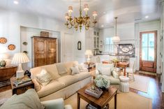 a living room filled with lots of furniture and a chandelier hanging from the ceiling