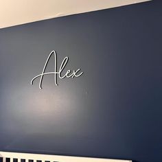 the name alex written in cursive writing on a wall next to a crib